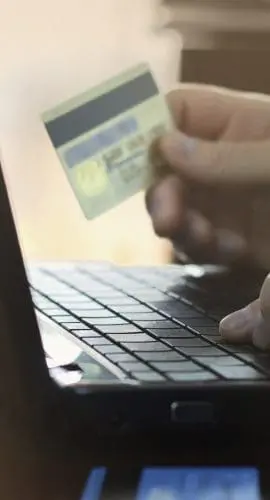 A person is typing on a laptop while holding a credit card.