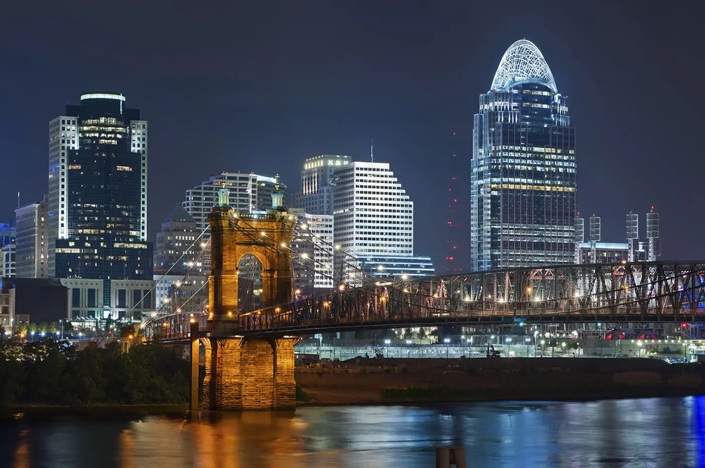 A nighttime cityscape showcases illuminated buildings and a bridge over a river, highlighting an urban skyline.