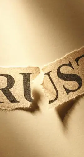 A piece of paper with the word "TRUST" torn into two parts.