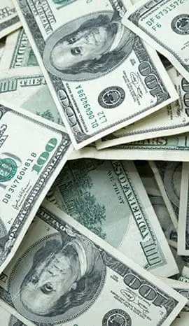 A pile of scattered US hundred-dollar bills.