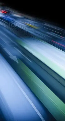 Vehicles captured in motion at night, creating streaks of light due to long exposure photography.