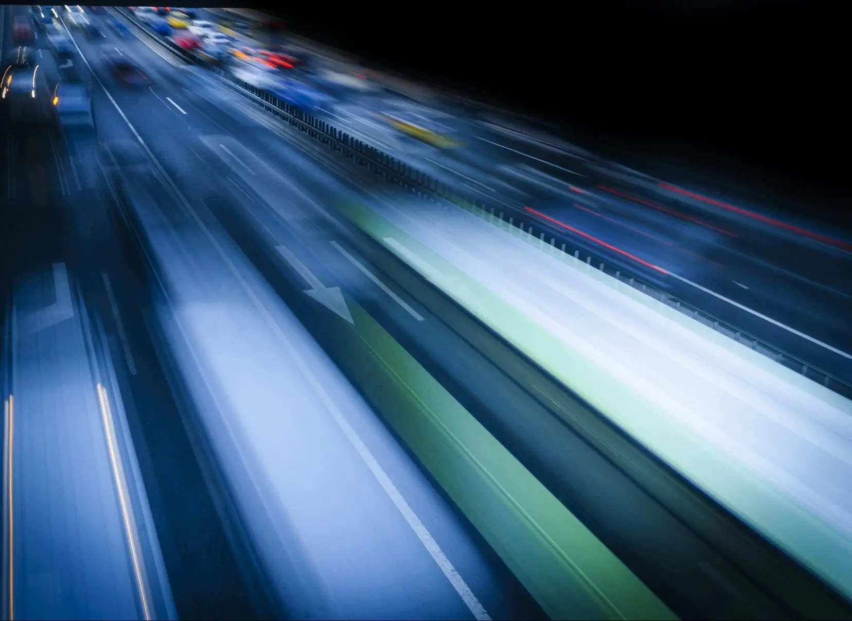Vehicles captured in motion at night, creating streaks of light due to long exposure photography.