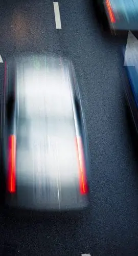 Vehicles captured in motion blur are traveling on a road, creating a sense of speed and movement.
