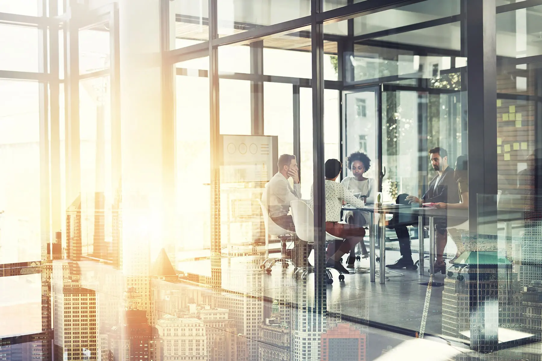 A group of professionals is engaged in a meeting in a modern office space bathed in sunlight.
