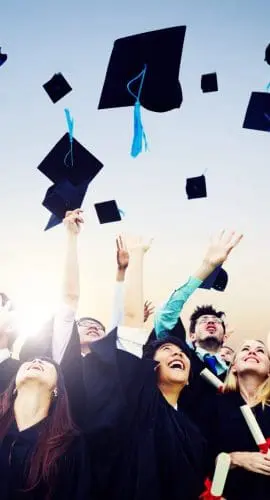 Smiling Students Throwing Graduation Caps In Air