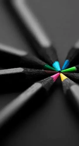 A group of pencils with colored tips arranged in a circular pattern on a dark background.