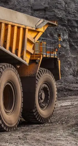 Large mining trucks and machinery operate in a rocky excavation site.