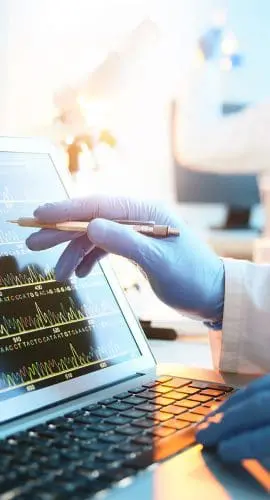 A person is analyzing a graph on a laptop screen in a laboratory environment.