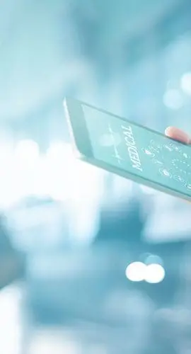 A healthcare professional is examining a digital tablet x-ray with a blurred hospital corridor in the background.