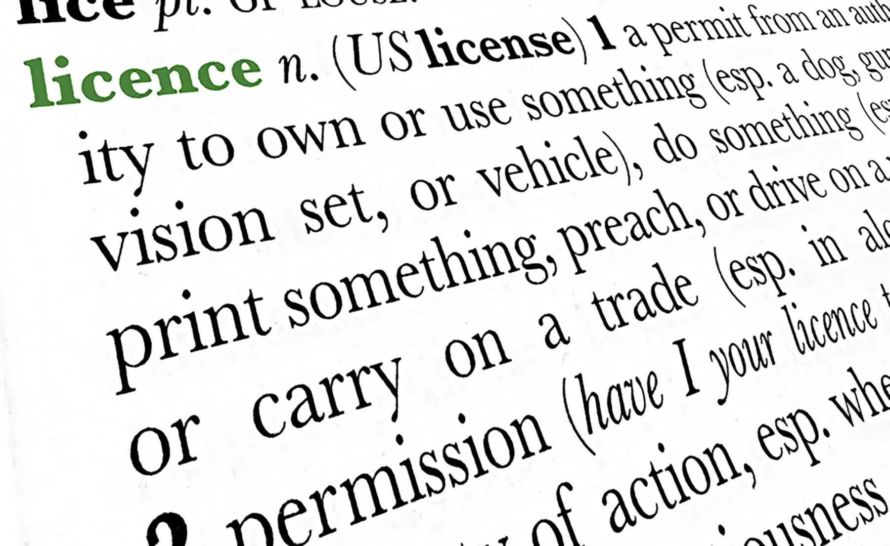 A close-up of a dictionary page showing the definition of the word "licence" with an alternative spelling "license."
