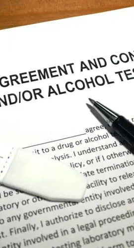 A document titled "EMPLOYEE AGREEMENT AND CONSENT TO DRUG AND/OR ALCOHOL TESTING" with a pen and a swab on top of it.
