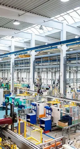 An industrial facility with machinery and equipment, potentially for manufacturing or assembly, is depicted with bright lighting and a clean, organized layout.