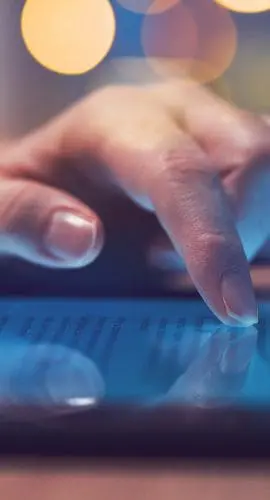 A person is using a tablet with a blurred colorful background.