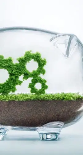 A clear piggy bank contains soil and lush green plants shaped like gear cogs, symbolizing financial growth or eco-friendly investments.