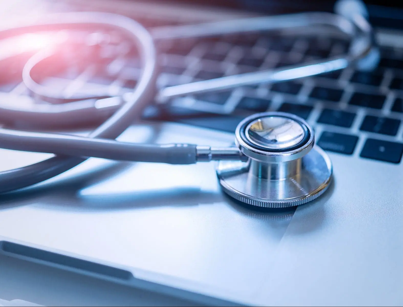 A stethoscope rests on an open laptop keyboard.