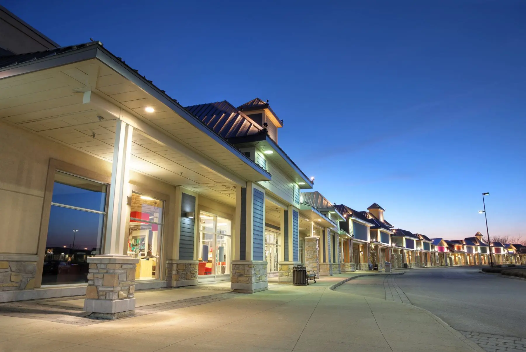 Modern retail shopping center at dusk, representing commercial properties in sale-leaseback transactions for real estate investors