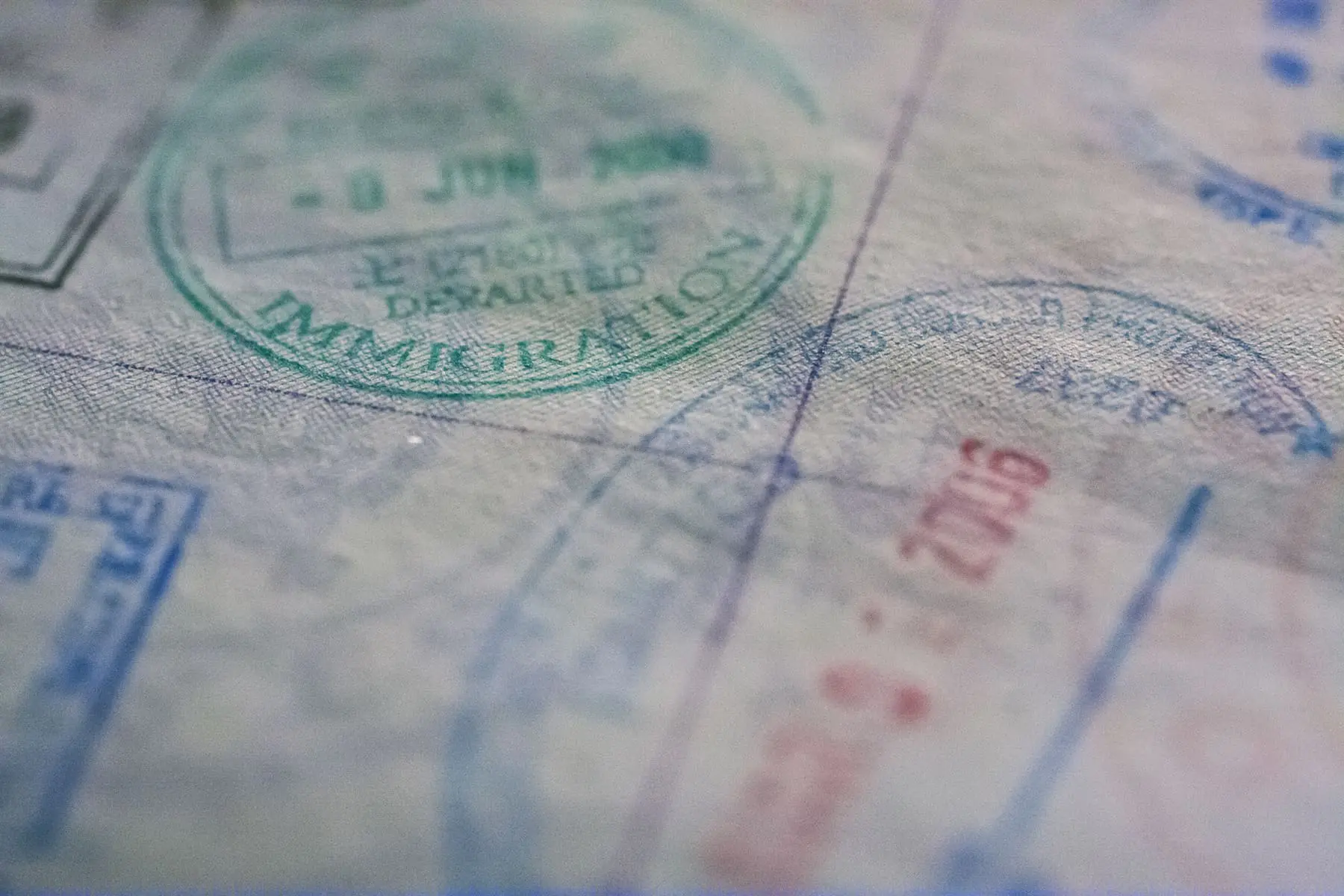 A close-up of various immigration and travel stamps on a passport page.