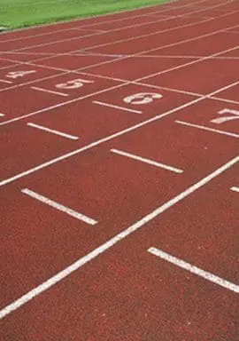 A red running track with numbered lanes curves around a grassy field.