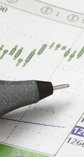 A pen rests on a financial chart displaying stock market data and trends.