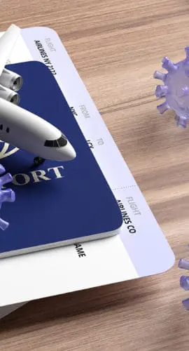 A model airplane, passports, stethoscope, and virus illustrations are arranged on a wooden surface.