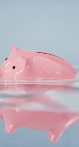 A pink piggy bank is floating on a water surface.