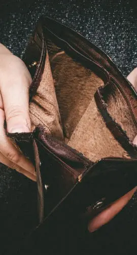 A person is holding an empty wallet, showing the inside.