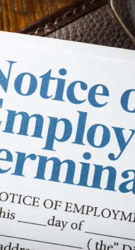 A document titled "Notice of Employment Termination" is partially covered by a pair of glasses.