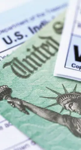 Various tax forms, including a 1040 and a W-2, are displayed alongside a depiction of the Statue of Liberty.