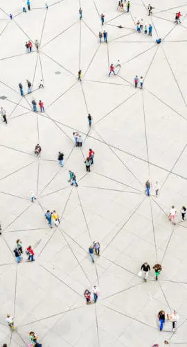 People are standing and walking on a large, open space marked with intersecting lines.