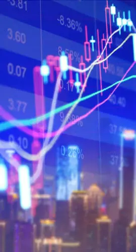 A colorful stock market chart is superimposed over a blurred cityscape at night.