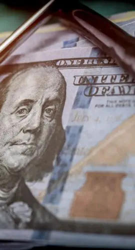 A stethoscope rests on top of several U.S. hundred-dollar bills.