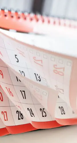 A desk calendar with pages turning, displaying dates.