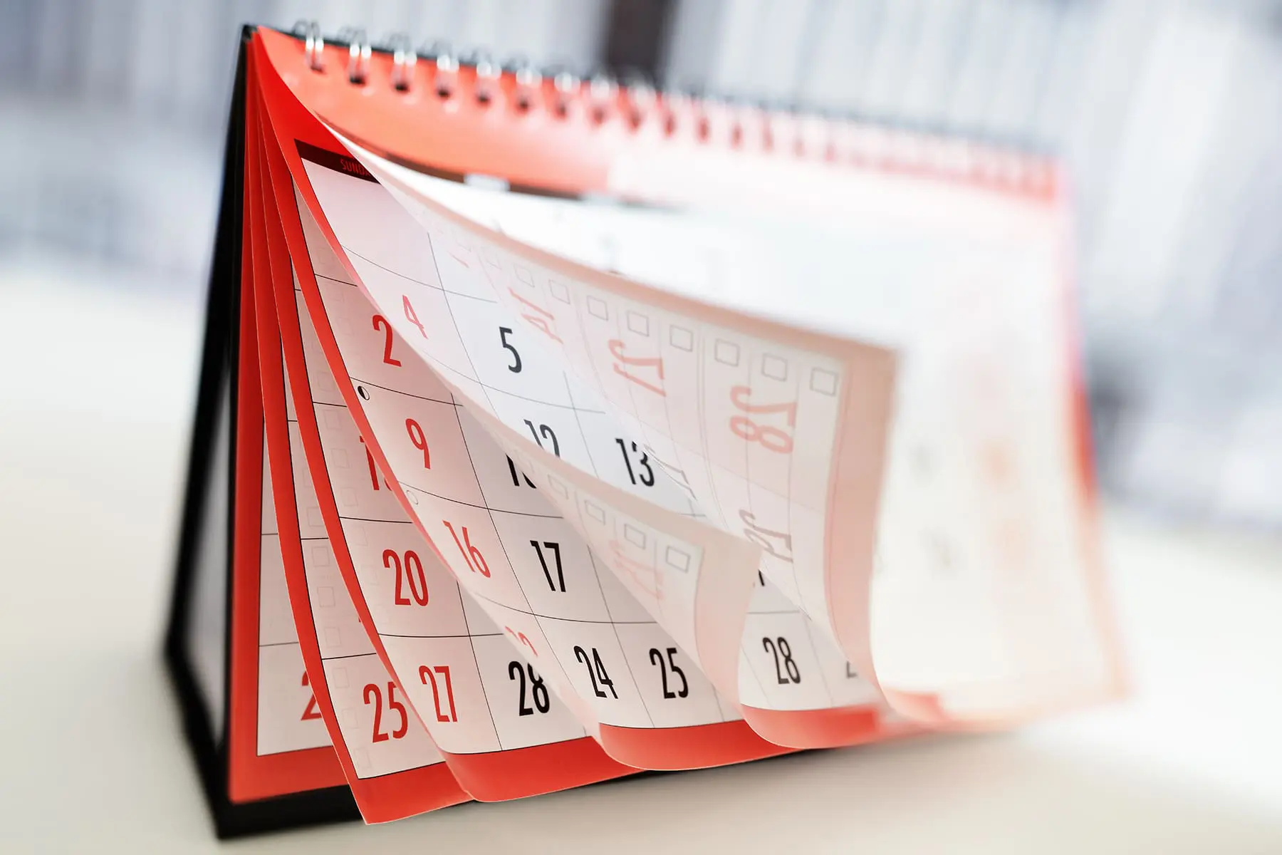 A desk calendar with pages turning, displaying dates.