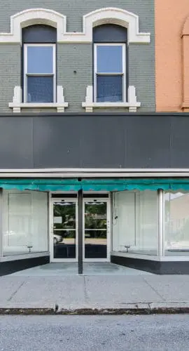 A row of storefronts with large display windows and colorful upper facades.