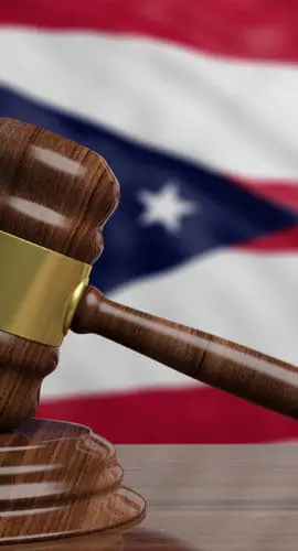 A judge's gavel is positioned in front of an Ohio state flag.