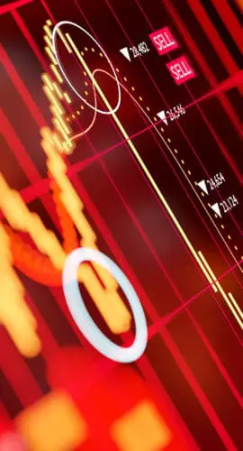 A red-dominated screen displays fluctuating financial stock or market data with graphs and charts.