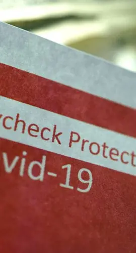 A document labeled "Paycheck Protection Program Covid-19" is partially visible with money in the background.