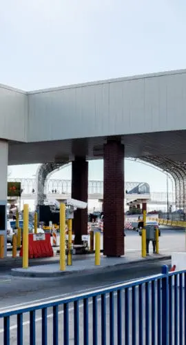 A border crossing checkpoint with multiple lanes is equipped with toll booths and barriers.