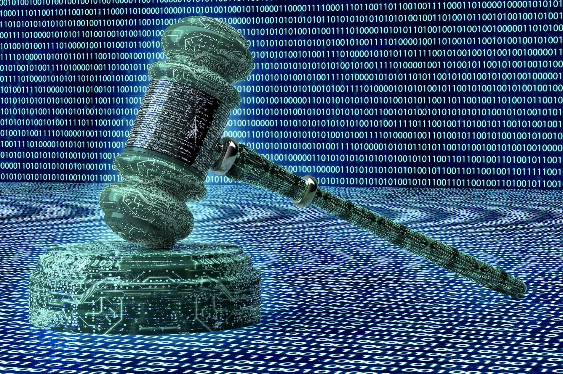 A gavel made of digital code rests on a surface with rows of binary digits in the background.