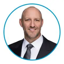 A person in a suit and tie is smiling inside a circular frame with a blue border.