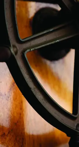 A ship's steering wheel mounted on a wooden surface with soft lighting highlighting its texture.