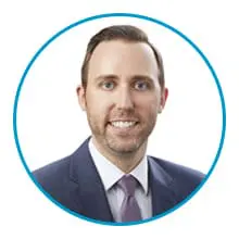 A man wearing a suit and tie is shown within a blue circular frame.