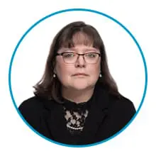 A person with glasses and shoulder-length hair is wearing a black jacket over a lace top and pearl necklace, set against a white background encircled by a blue border.