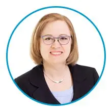 A person wearing glasses and a blazer is smiling at the camera, framed within a blue circle.