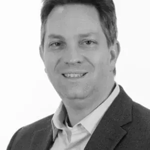 A person in professional attire, smiling and looking at the camera, against a plain background.