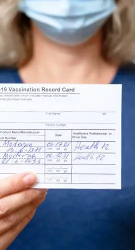 Moscow - Sep 12, 2021: Vaccinated young woman showing COVID-19 Vaccination Record Card, healthy person in mask after getting corona virus vaccine. Coronavirus vaccine shot and immunization mandate.