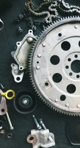 A collection of various mechanical parts and tools is spread out on a dark surface.