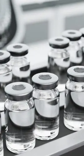 Rows of capped vials are lined up in a production or laboratory setting.