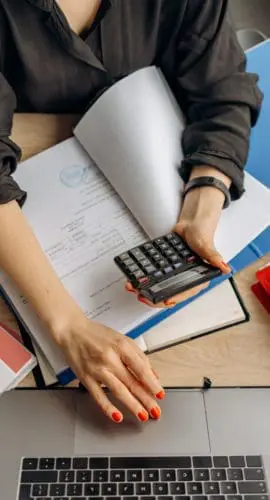 Person holding black calculator while using laptop