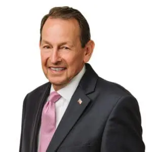 A man in a suit and pink tie is smiling at the camera.